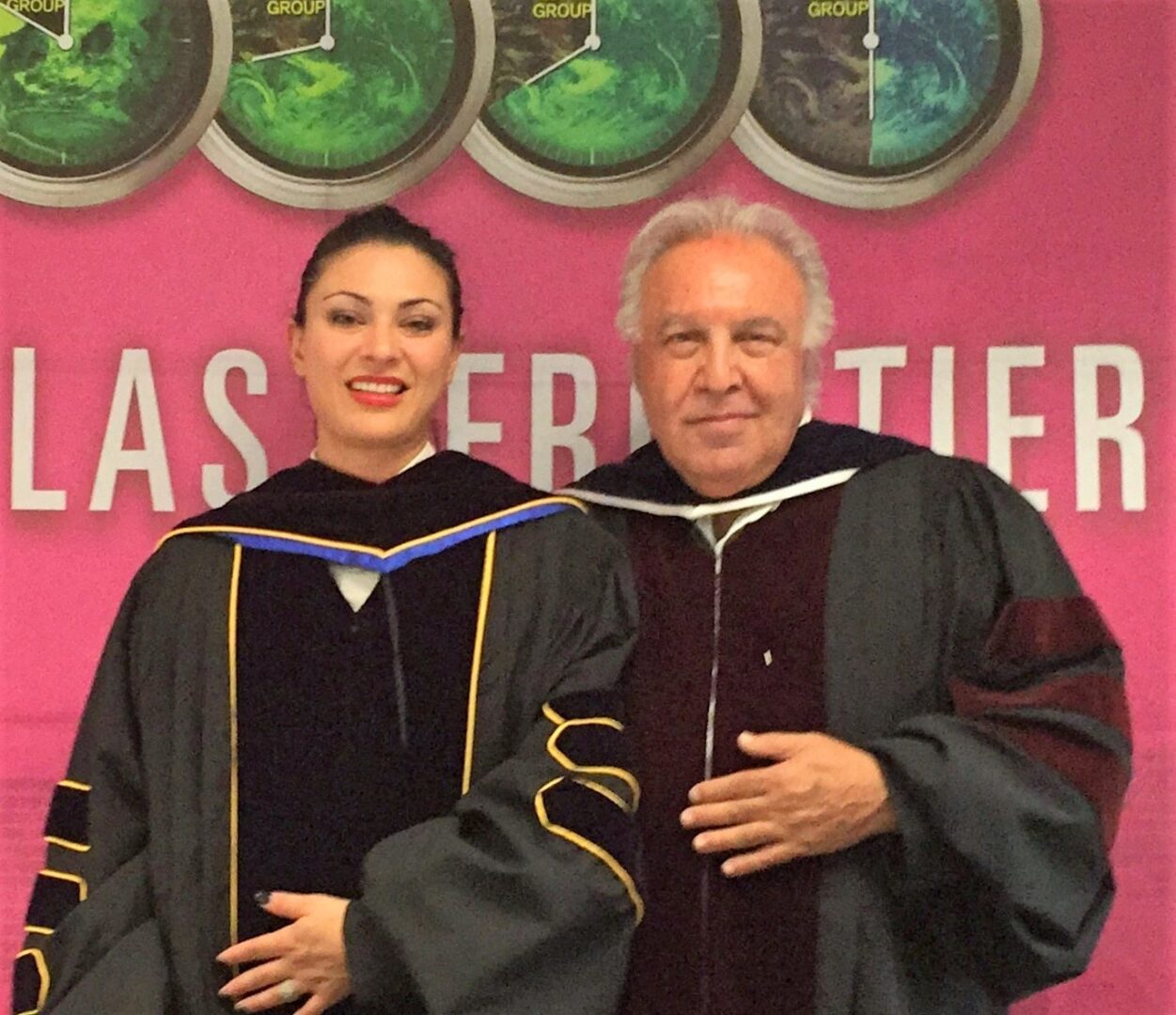 Two people in graduation gowns posing for a picture.
