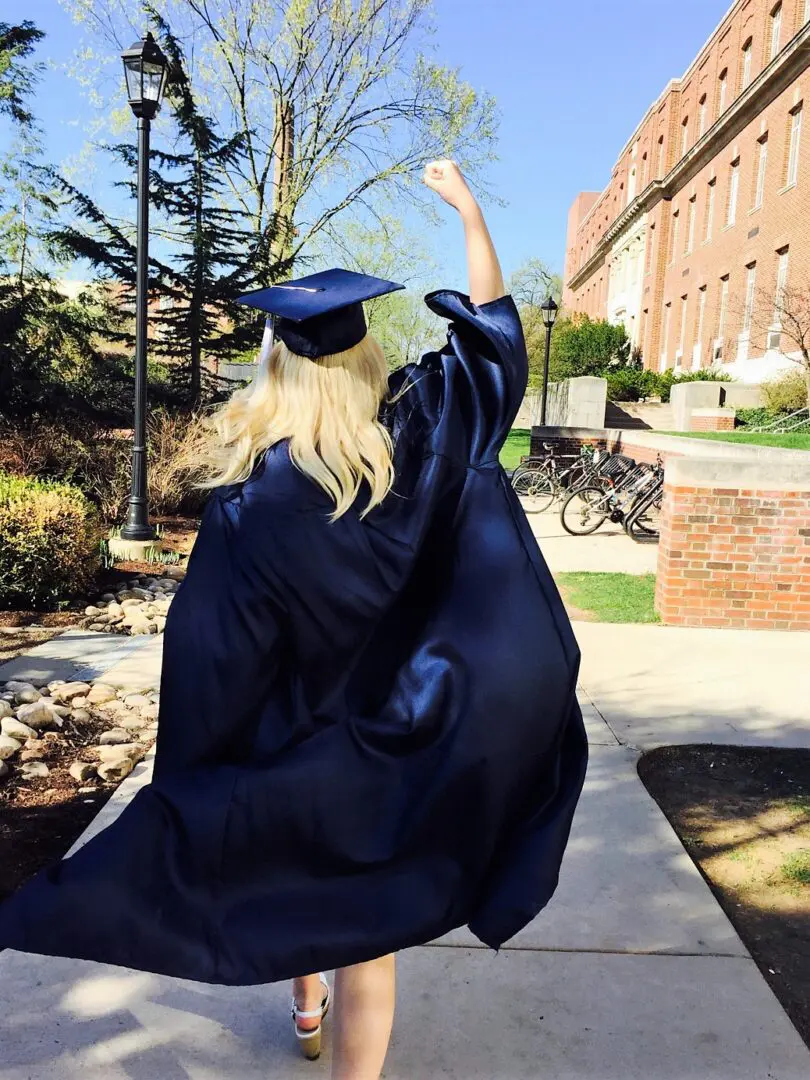 A person in a cap and gown jumping into the air.