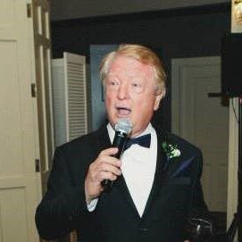 A man in a tuxedo is holding a microphone.